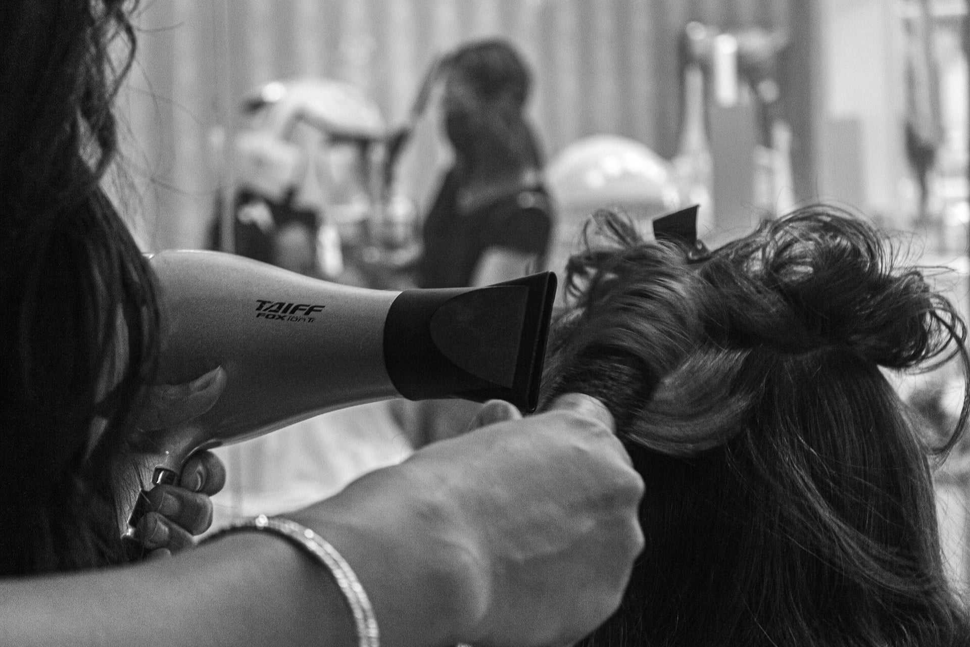 Hair stylist drying a client's hair in a salon setting.